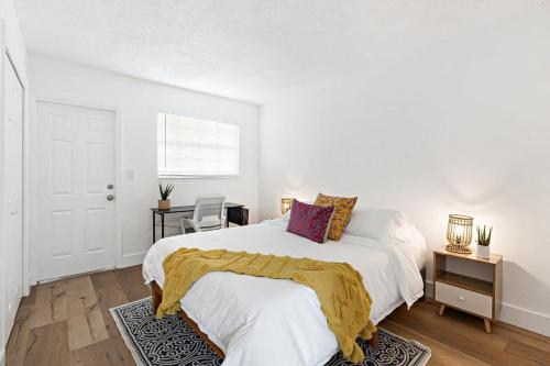 a white bedroom with a bed and a desk at Stylish 2 BR condo - close to Riverwalk in Fort Lauderdale