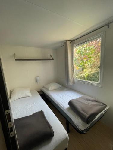 two beds in a small room with a window at Vacances en Provence en mobil home in La Roque-dʼAnthéron
