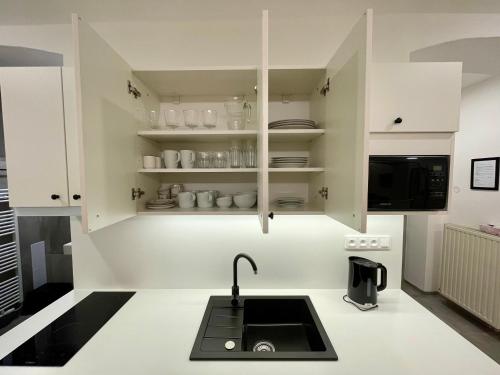 a kitchen with white cabinets and a sink at Pension Phoenix in Znojmo