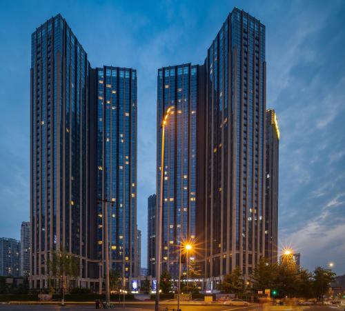 Chengdu Yayu Aparthotel في تشنغدو: ناطحات السحاب الثلاثة طويلة في المدينة ليلا