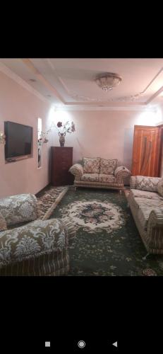 uma sala de estar com sofás e uma televisão de ecrã plano em Квартира em Samarkand