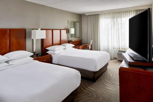 a hotel room with two beds and a flat screen tv at Detroit Metro Airport Marriott in Romulus