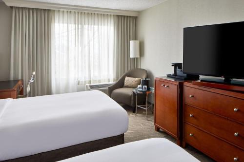 a hotel room with a bed and a flat screen tv at Detroit Metro Airport Marriott in Romulus