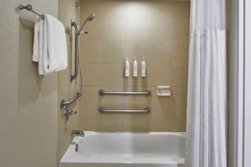 a bathroom with a tub and a shower with towels at Detroit Metro Airport Marriott in Romulus