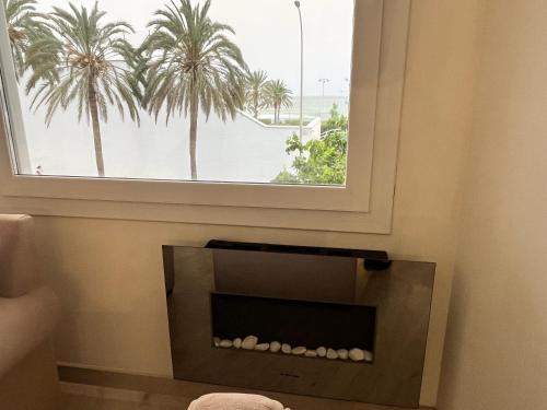 a fireplace in a room with a window with palm trees at Ruby malagueta in Málaga