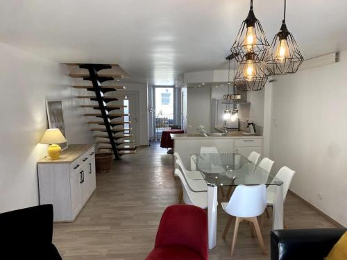 une salle à manger et une cuisine avec une table et des chaises en verre dans l'établissement Maison de ville des Bernardines, à Orgelet