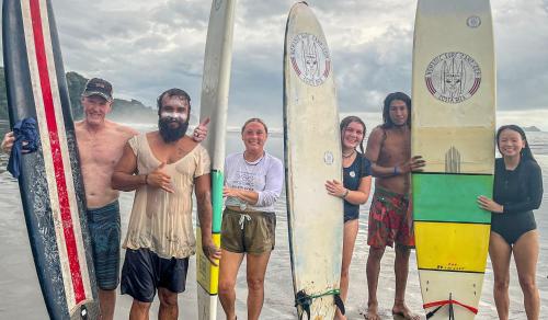 a group of people standing on the beach with surfboards at Nomadic Surf Camp in Uvita