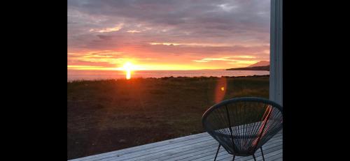 a view of a sunset from a porch with a chair at Brimslóð Atelier Guesthouse in Blönduós