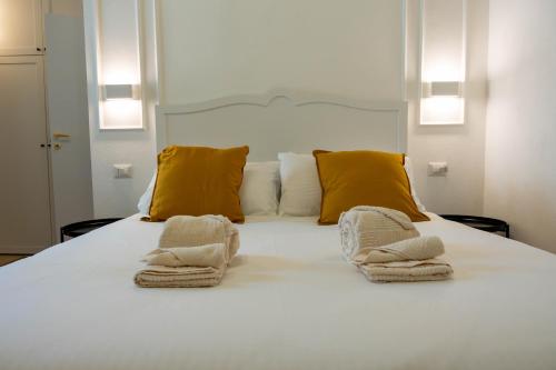 a white bed with yellow pillows and towels on it at Gala Sardinia in Cagliari