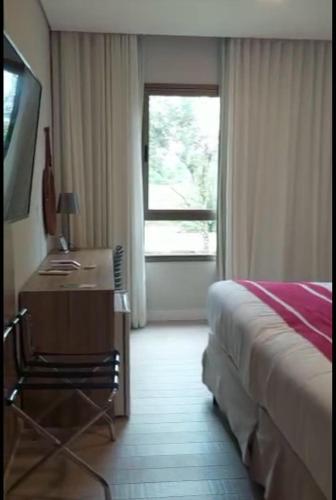a bedroom with a desk and a bed and a window at Adriana Rinaldi Gonçalves in Angra dos Reis