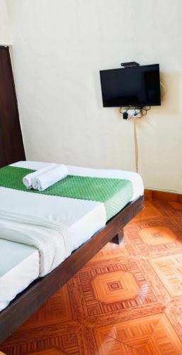 a bed in a room with a tv on the wall at Baga Beach Paradise in Baga