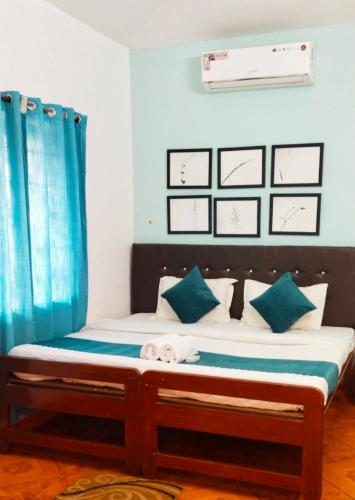 a bed in a room with a blue curtain at Baga Beach Paradise in Baga