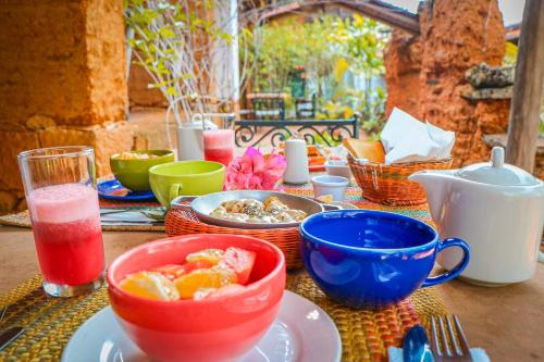 a table with bowls and plates of food and a drink at Hotel El Cogollo By MH in Barichara