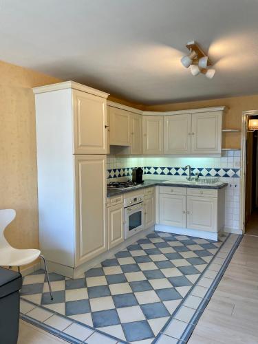 - une cuisine avec des placards blancs et un sol en damier dans l'établissement Studio Ti’Sable 50m de la plage, à Fort-Mahon-Plage