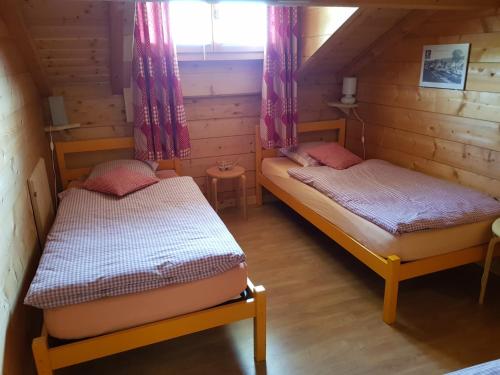 2 łóżka w małym pokoju z oknem w obiekcie Les Genévriers w mieście Foncine-le-Haut