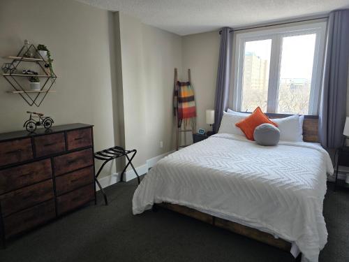 a bedroom with a bed with a window and a dresser at Smart Stylish Downtown Condo- 2 bedrooms in Saskatoon