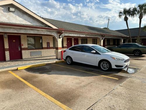 a white car parked in a parking lot in front of a building at Palace Inn I-45 & Bellfort in Houston