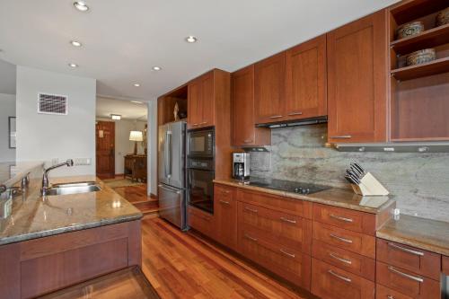 a kitchen with wooden cabinets and stainless steel appliances at Kaanapali Alii in Lahaina