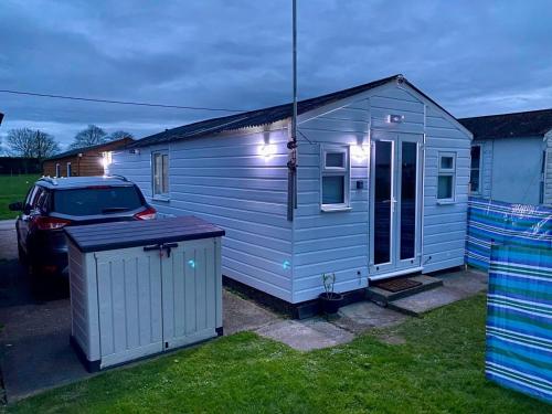 a small blue house with a car parked next to it at All Seasons Chalet Breaks in Leysdown-on-Sea