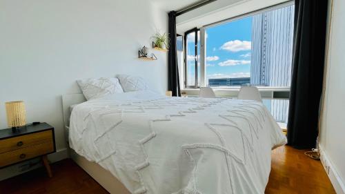 ein Schlafzimmer mit einem weißen Bett und einem großen Fenster in der Unterkunft Montparnasse, 2 cozy private rooms in shared apartment in Paris