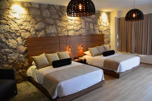 een slaapkamer met 2 bedden en een stenen muur bij Ilo Rojo Hotel Boutique in San Miguel de Allende