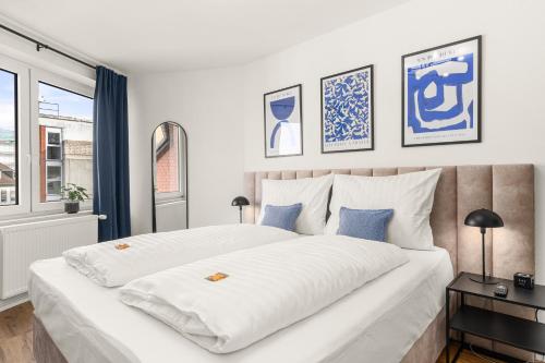 1 dormitorio con 1 cama blanca grande con almohadas azules en BLU APARTMENT -modern interior design in city centre- Nähe Uni & HBF en Kassel