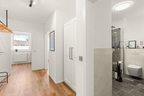 uma casa de banho branca com um chuveiro e um WC. em BLU APARTMENT -modern interior design in city centre- Nähe Uni & HBF em Kassel