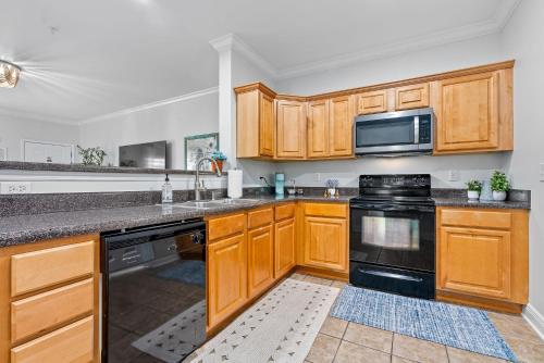 a kitchen with wooden cabinets and black appliances at Walk to Arena and Downtown Auburn in Auburn