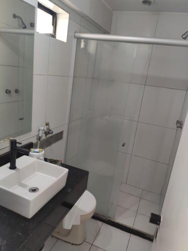 uma casa de banho branca com um lavatório e um chuveiro em Flat na Praia de Iracema 105 em Fortaleza