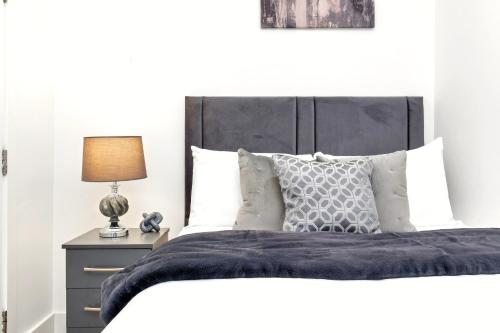 uma cama com uma cabeceira preta e uma mesa com um candeeiro em NEW Balfour House by Truestays - 5 Bedroom House in Stoke-on-Trent em Etruria