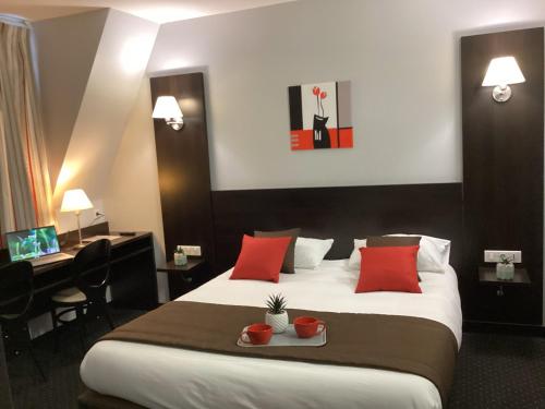 una habitación de hotel con una cama grande con almohadas rojas en Hôtel Alliance, en Lourdes