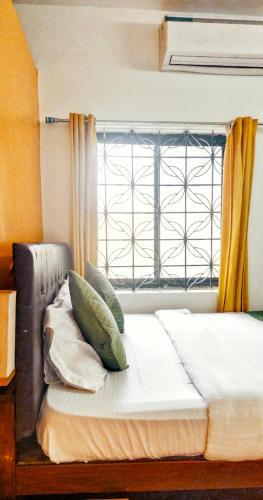 a bed with pillows sitting in front of a window at Baga Beach Paradise in Baga