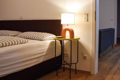 Una cama con una mesa con una lámpara. en Ferienwohnung Bodenseeblick Nr 9 en Scheidegg