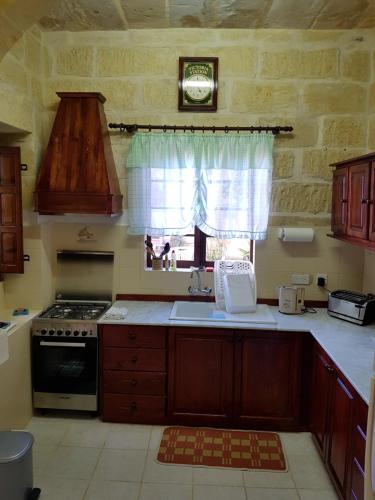 une cuisine avec évier et cuisinière ainsi qu'une fenêtre dans l'établissement Jenkins Holiday Farmhouse, à L-Għarb