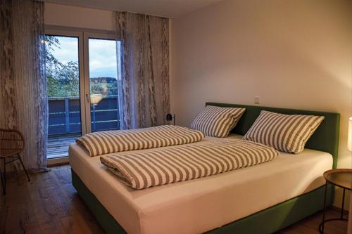 een slaapkamer met 2 bedden en een groot raam bij Ferienwohnung Bodenseeblick Nr 7 in Scheidegg