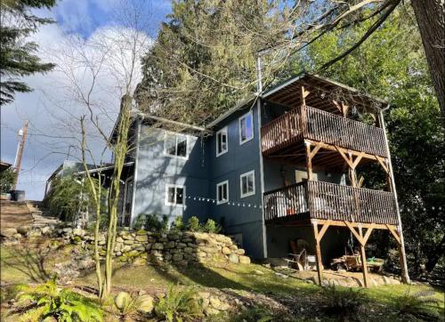 a blue house with a balcony on a hill at Riverside Retreat in Gold Bar