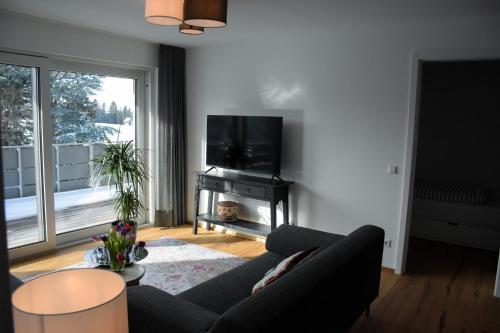 a living room with a couch and a flat screen tv at Ferienwohnung Bodenseeblick Nr 8 in Scheidegg