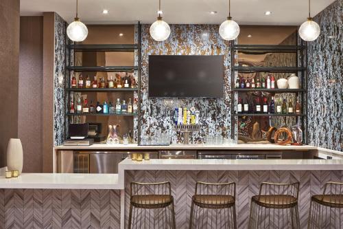 a bar in a hotel with stools and a tv at SpringHill Suites by Marriott Los Angeles Downey in Downey