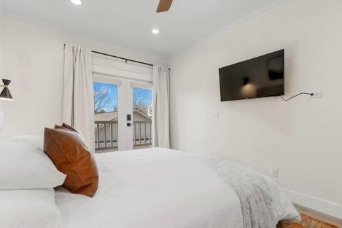 a white bedroom with a bed and a flat screen tv at 27 on Park Boutique Hotel & Venue in Dahlonega