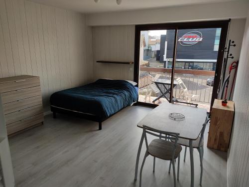 a bedroom with a bed and a table and a window at Studio proche centre-ville et gare in Dax