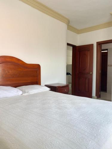 a bedroom with a large bed with a wooden headboard at Aparta Hotel Caribe Paraiso in Juan Dolio