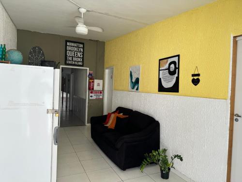 a room with a black couch against a yellow wall at Casa Recife Pousada in Recife
