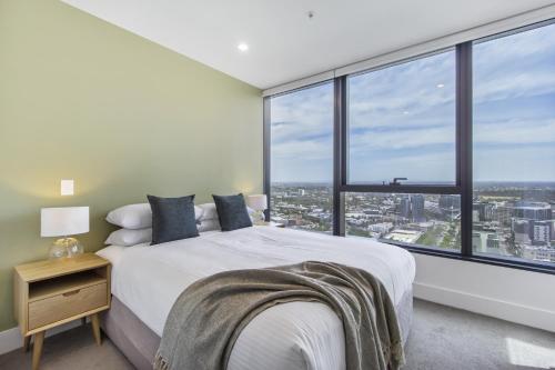 a bedroom with a white bed and large windows at Atop the Melbourne CBD with Panoramic Views in Melbourne