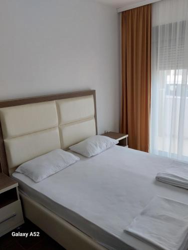 1 dormitorio con 1 cama grande con sábanas blancas y ventana en Aria Ulcinj, en Ulcinj
