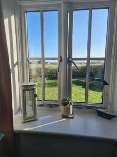 ein Fenster mit Blick auf ein grünes Feld in der Unterkunft Brisley North Norfolk cosy cottage garden pub and walks in Beetley