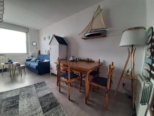 un salon avec une table et un canapé bleu dans l'établissement Le Petit Noirmout, à LʼHerbaudière