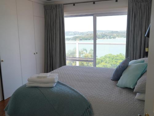 a bedroom with a bed with a large window at Luxury Palms in Paihia