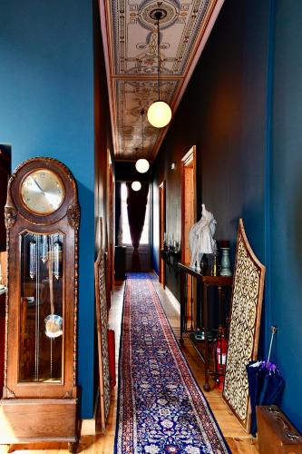 a hallway with a grandfather clock and blue walls at VASILIKON Hotel 1888 the past is present HISTORICAL PRESERVATION MONUMENT in Kalamata