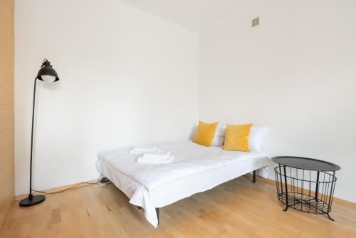 a white bed with yellow pillows and a table at Metro Ratusz Arsenał Comfort Studio in Warsaw