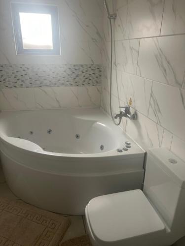 a white bathroom with a tub and a toilet at Modern 4 Bed House for 9 guests in Tilbury